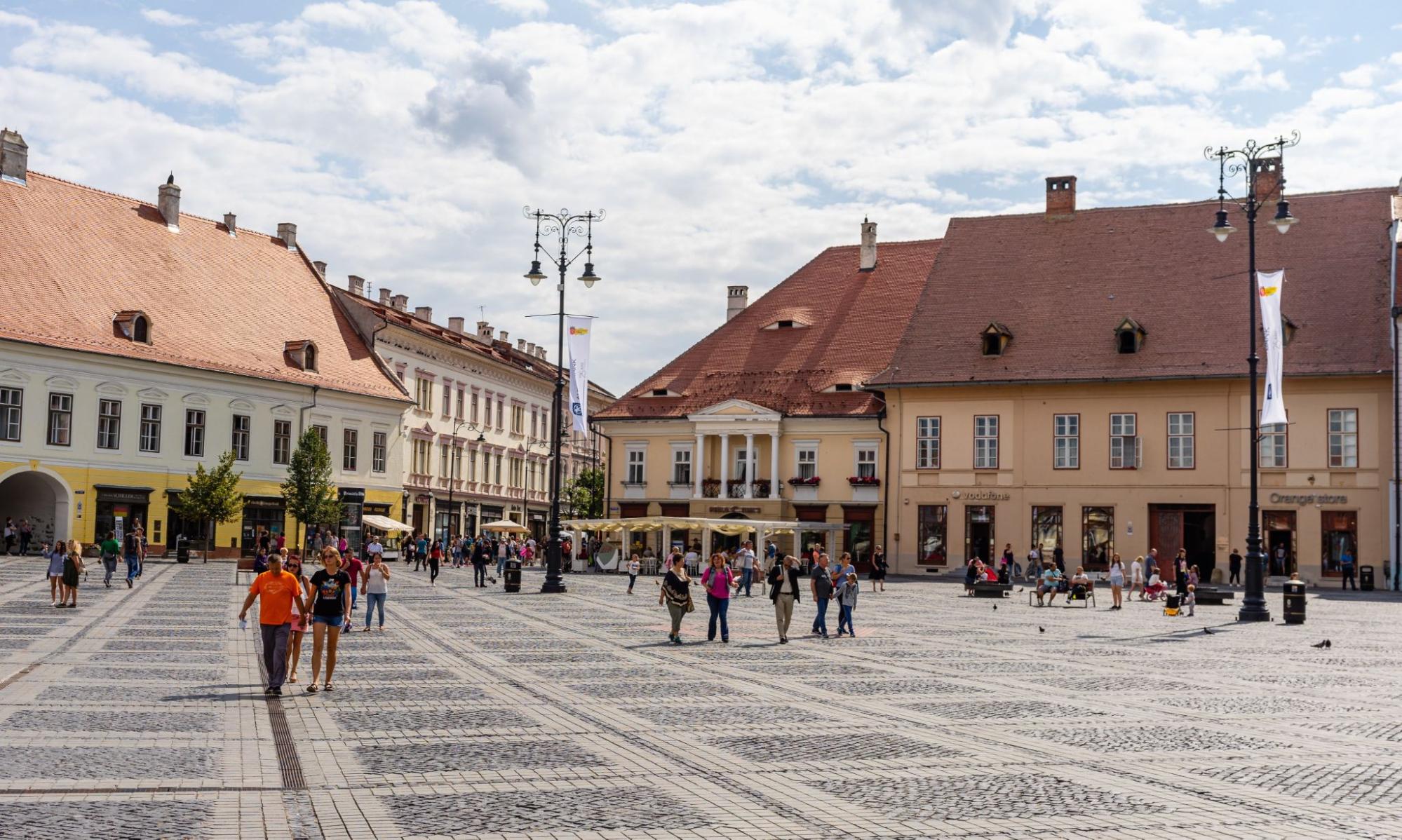 Tourist wondering in the panoramic The Big Square (Piata Mare) of Sibiu looking and the City hall