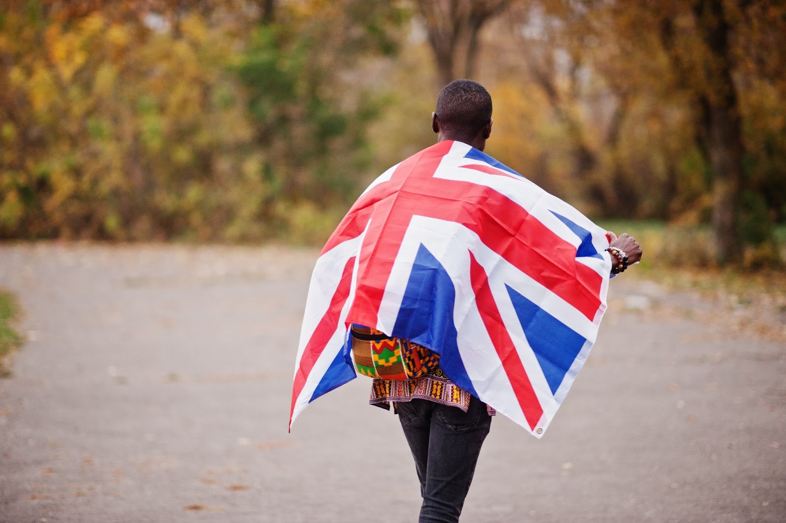African man in africa traditional shirt on autumn park with Great Britain flag